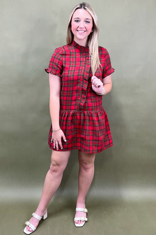 Woman wearing a red plaid dress against a plain background