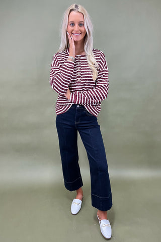 Burgundy and white striped long sleeve henley top with button front styled with dark wide leg cropped jeans and white loafers