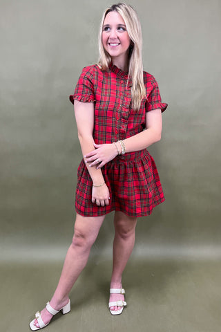 Woman wearing a red plaid dress against a plain background