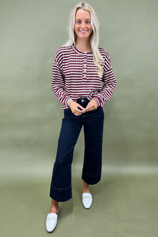 Burgundy and white striped long sleeve henley top with button front styled with dark wide leg cropped jeans and white loafers