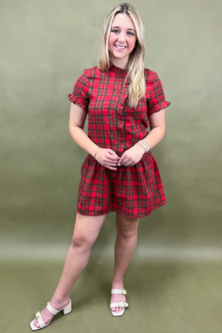 Woman wearing a red plaid dress against a green background