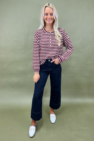 Burgundy and white striped long sleeve henley top with button front styled with dark wide leg cropped jeans and white loafers