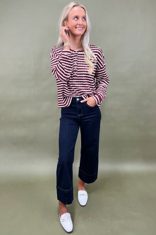 Burgundy and white striped long sleeve henley top with button front styled with dark wide leg cropped jeans and white loafers