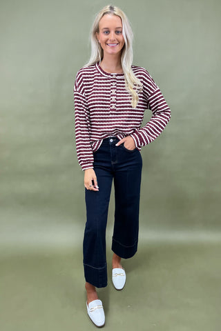 Burgundy and white striped long sleeve henley top with button front styled with dark wide leg cropped jeans and white loafers
