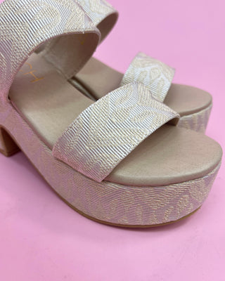 Beige platform sandals with ribbed straps on a pink background