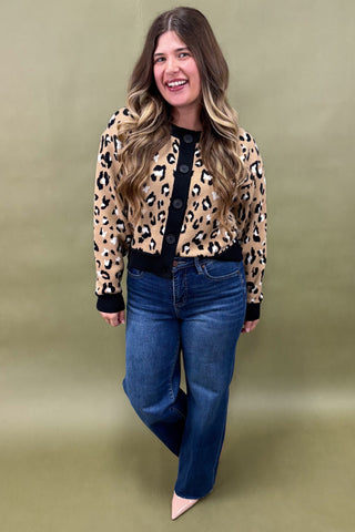 Woman wearing a leopard print jacket and blue jeans on a green background