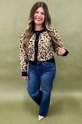 Woman wearing a leopard print jacket and blue jeans on a green background