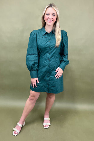 Woman wearing a teal dress against a plain background