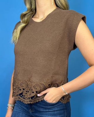 Chocolate brown sleeveless knit top with structured shoulders and an intricate embroidered lace hem.