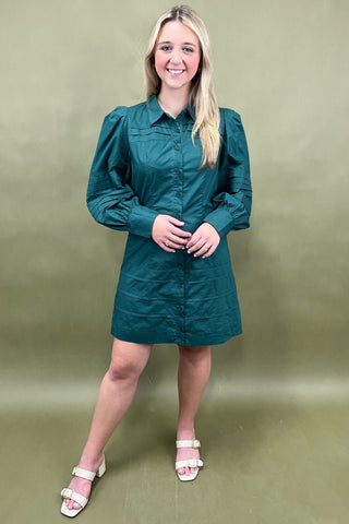 Woman wearing a teal dress against a plain background