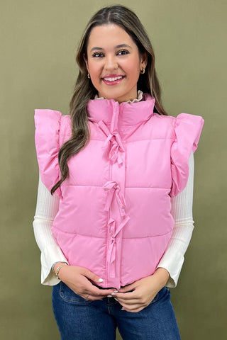 Woman wearing a pink puffer vest against a green background