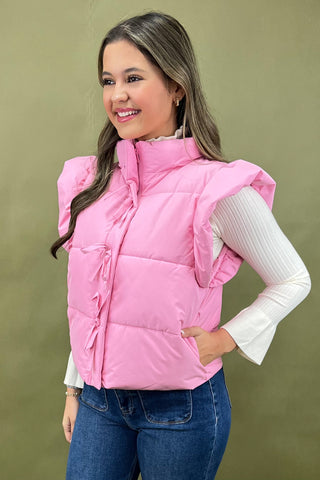 Woman wearing a pink puffer vest against a green background