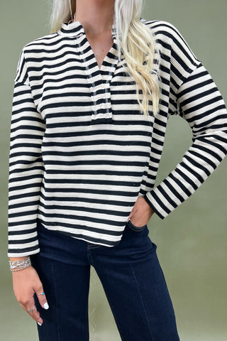 Person wearing a black and white striped long-sleeve top with a plain background