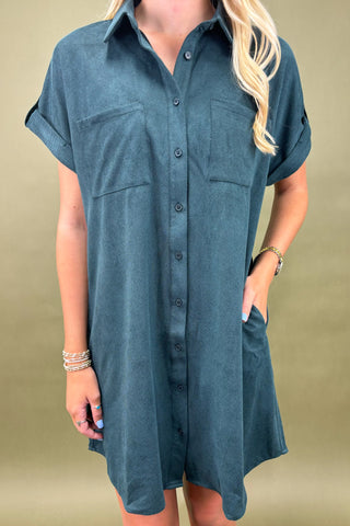Woman wearing a teal button-up dress against a beige background