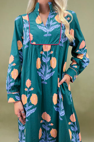 Woman wearing a green dress with floral pattern against a beige background
