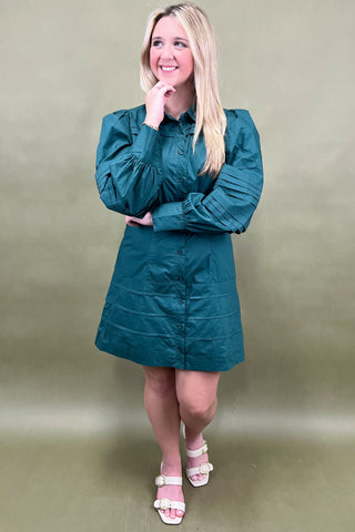 Woman wearing a teal dress against a plain background