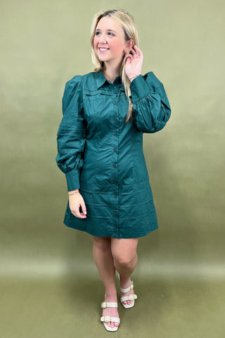 Woman wearing a teal dress against a beige background