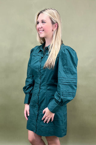 Woman wearing a teal jacket against a beige background
