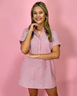 Woman wearing a red and white striped dress against a pink background