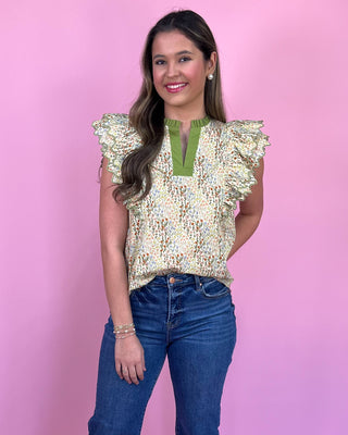 Woman wearing a sequined top and jeans against a pink background
