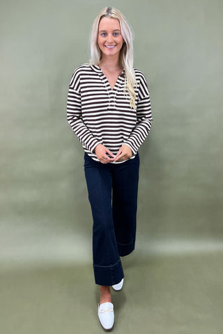Brown and white striped long sleeve henley top styled with dark wide leg cropped jeans and white loafers.