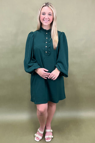 Woman wearing a green dress against a beige background