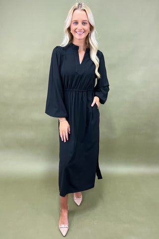 Woman wearing a black dress against a plain background