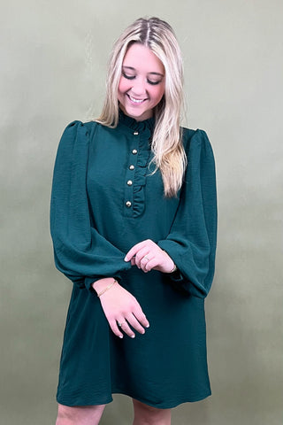 Woman wearing a green dress with puffed sleeves against a beige background