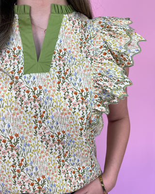 Floral patterned top with ruffled sleeves on a pink background