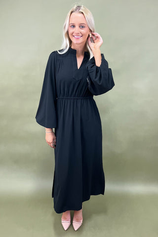 Woman wearing a black dress against a green background