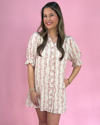 Woman wearing a floral dress against a pink background