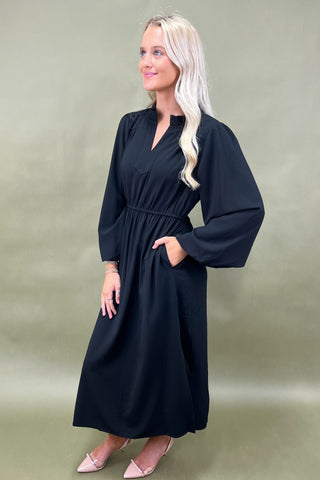 Woman wearing a black dress against a plain background