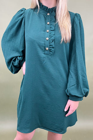Teal dress with puffed sleeves worn by a person against a plain background