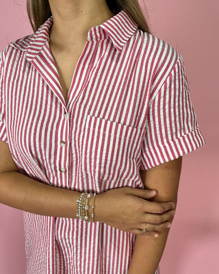 Person wearing a red and white striped shirt against a pink background