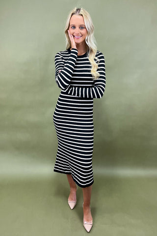 Woman wearing a black and white striped dress against a green background