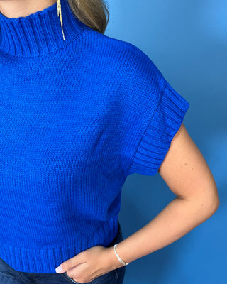 Royal blue turtleneck sleeveless knit sweater top with cap sleeves, ribbed trim, and a relaxed fit.