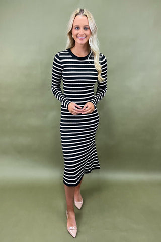 Woman wearing a black and white striped dress against a green background