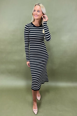 Woman wearing a black and white striped dress against a green background
