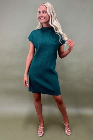 Woman wearing a teal dress against a plain background