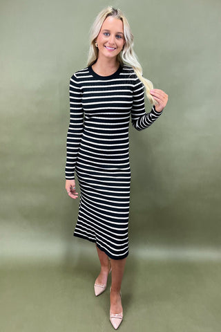 Woman wearing a black and white striped dress against a green background