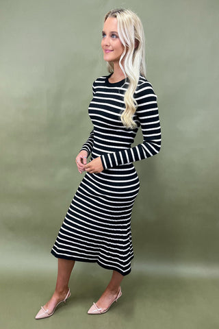 Woman wearing a black and white striped dress against a green background