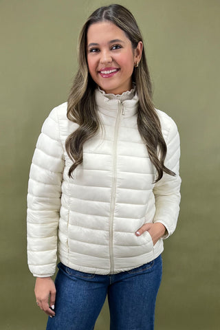 Woman wearing a white puffer jacket against an olive green background
