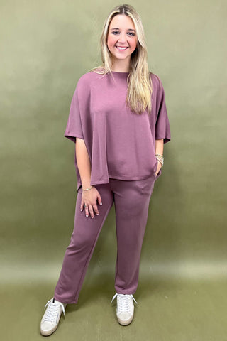 Woman wearing a mauve outfit with white sneakers against a green background