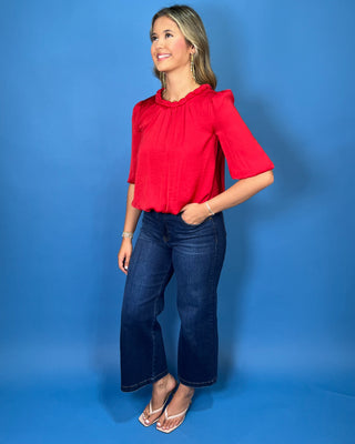 Red satin blouse with a braided neckline, structured shoulders, elbow-length sleeves, and a relaxed fit.