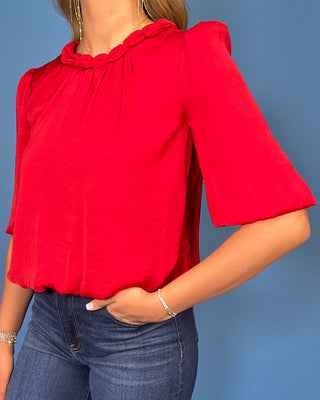 Red satin blouse with a braided neckline, structured shoulders, elbow-length sleeves, and a relaxed fit.