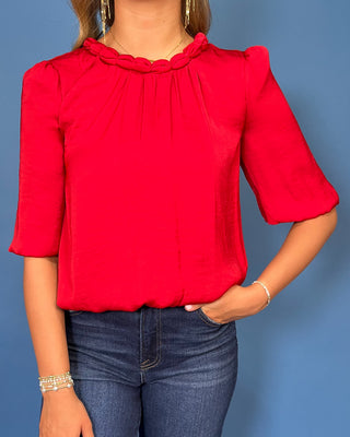 Red satin blouse with a braided neckline, structured shoulders, elbow-length sleeves, and a relaxed fit.