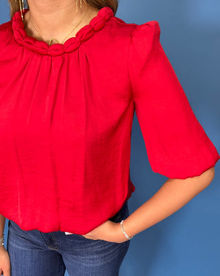 Red satin blouse with a braided neckline, structured shoulders, elbow-length sleeves, and a relaxed fit.