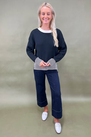 Black knit sweater with striped trim styled with dark wide leg cropped jeans and white loafers, casual fall outfit