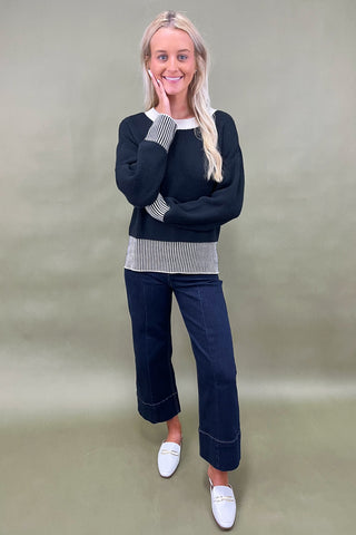 Black knit sweater with striped trim styled with dark wide leg cropped jeans and white loafers, casual fall outfit