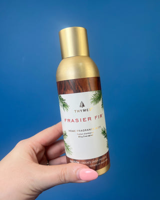 Thymes Frasier Fir Home Fragrance Mist bottle displayed on a solid blue background. 
